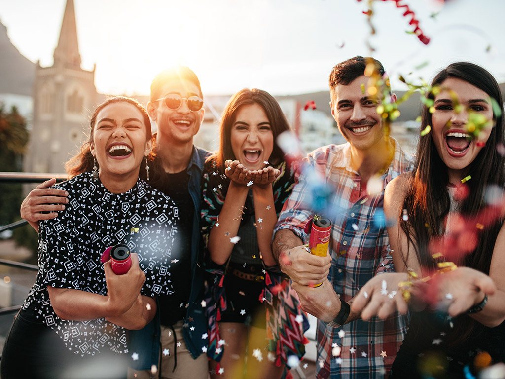 Friends enjoying party and throwing confetti